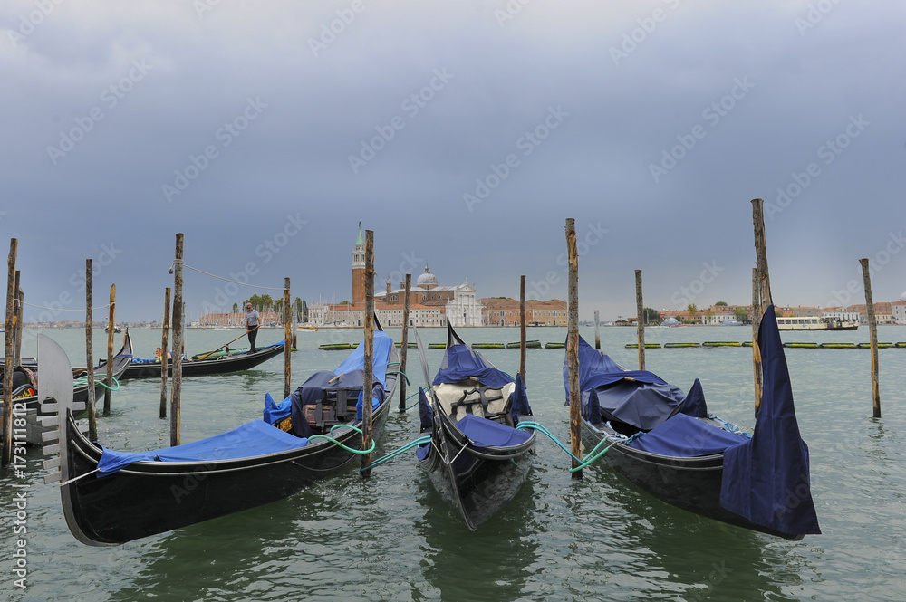 Traditional gondolas in the sea water on background of ancient Venice, Italy