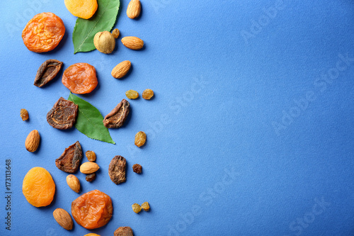 Dried apricots, raisins and nuts on color background