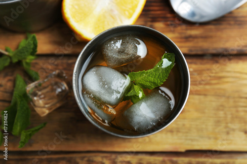 Metal glass with mint julep on wooden background