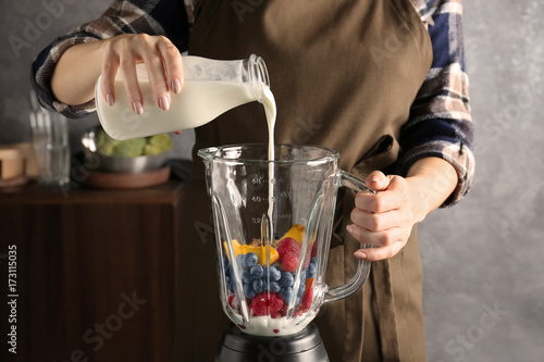 Young woman preparing smoothie in kitchen