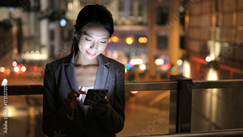 Business woman reading on cellphone at night