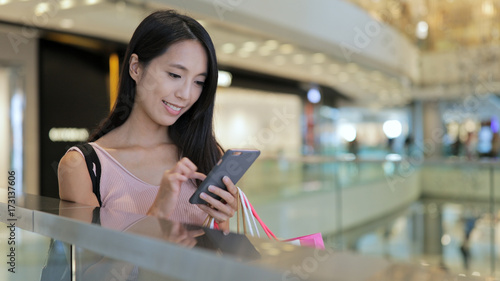 Woman using smart phone with shopping bags