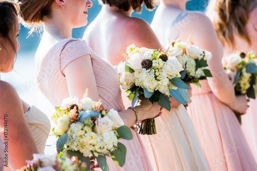 Pink bridesmaids in a row holding bouquet of flowers.