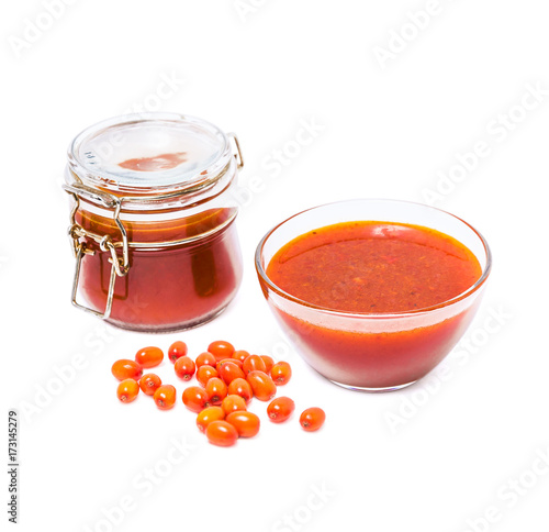 Fortified jam from fresh berries of sea buckthorn mashed with sugar in a glass jar, a vase with jam and berries in bulk isolated on white background