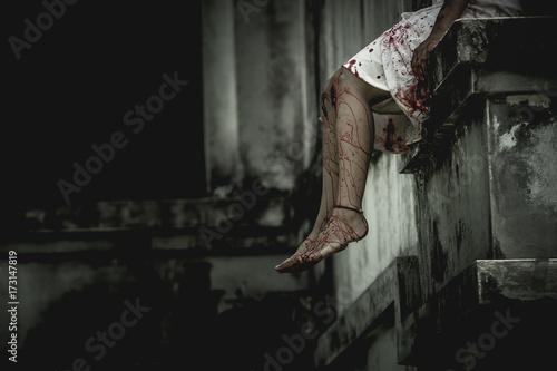 Zombie woman sitting on the edge of the window in an abandoned building on Halloween. Women dressed in zombie