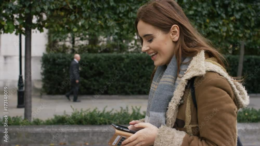 Attractive young female walking through the city using her phone Attractive young female walking through the city using her phone