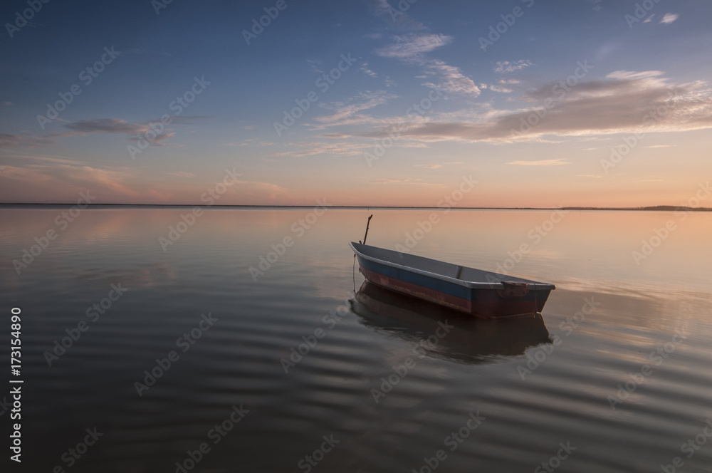 A small boat floats serenely on the sea water. The image contains soft focus when view at full resolution. A small boat floats serenely on the sea water. The image contains soft focus when view at full resolution.
