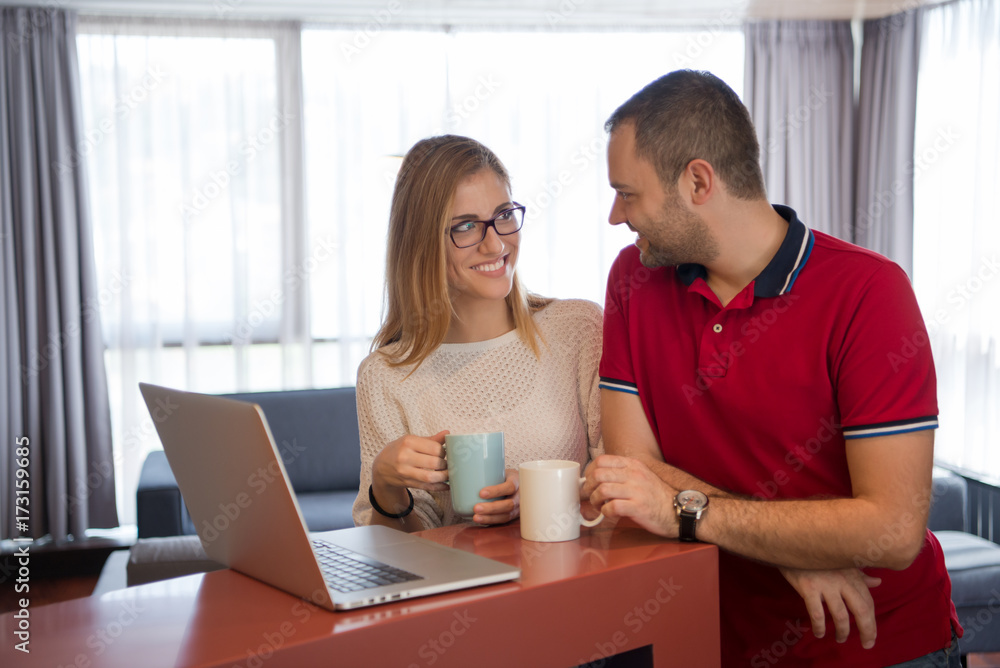 couple drinking coffee and using laptop at home couple drinking coffee and using laptop at home