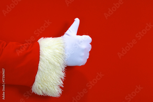 Santa Claus hand presenting your christmas text or product over red background with copy space