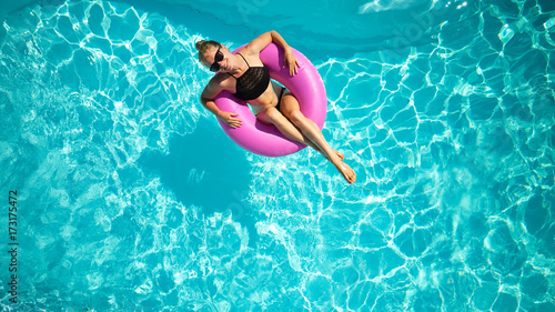 top view of young female swim with inflatable pink ring in pool