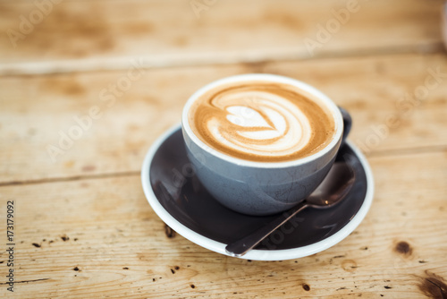 Cup of cappuccino with spoon on cosy wooden table