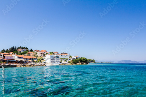 Rocky shallows with crystal clear water and beautiful settlement over blue sea