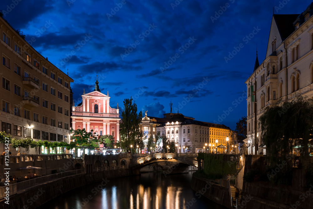 Triple Bridge and Franciscan Church of the Annunciation in the center of Ljubljana at night illuminated water color reflection night sky