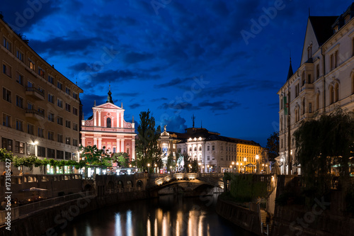 Triple Bridge and Franciscan Church of the Annunciation in the center of Ljubljana at night illuminated water color reflection night sky