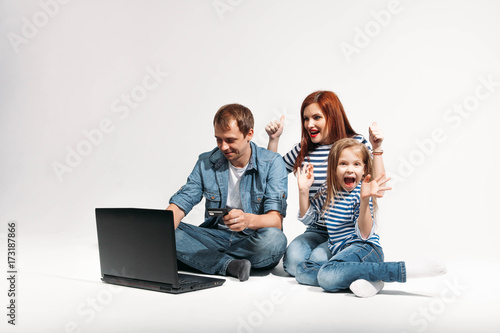 Happy family Father, mother and child lying on the floor with laptop credit card on white background isolated