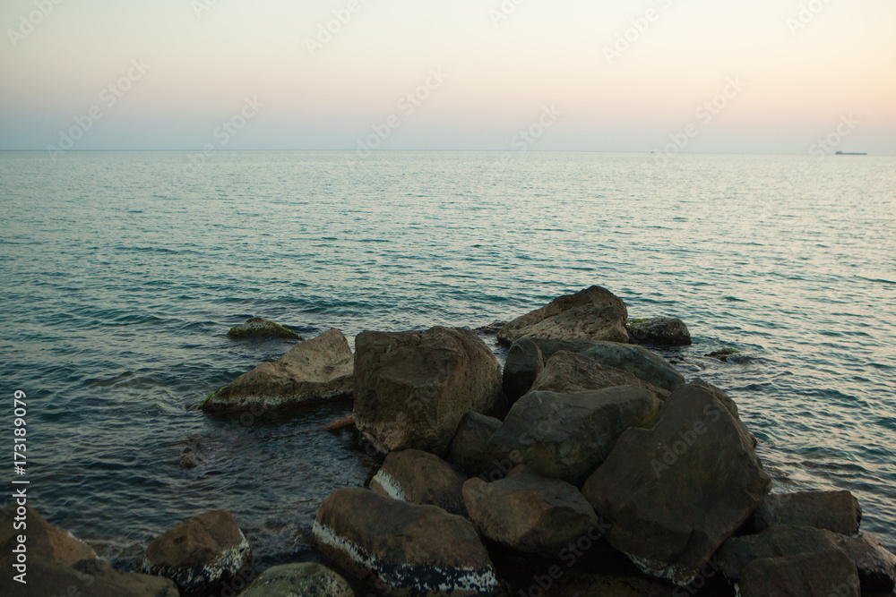 large dark stones lying in the sea in the evening at sunset