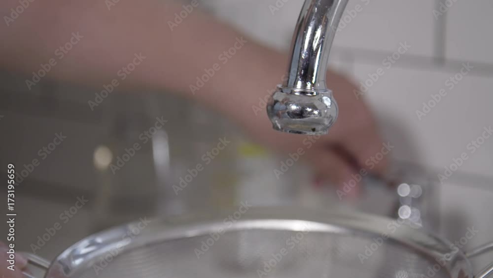 Slow motion, person turns faucet on over couscous in strainer Slow motion, person turns faucet on over couscous in strainer