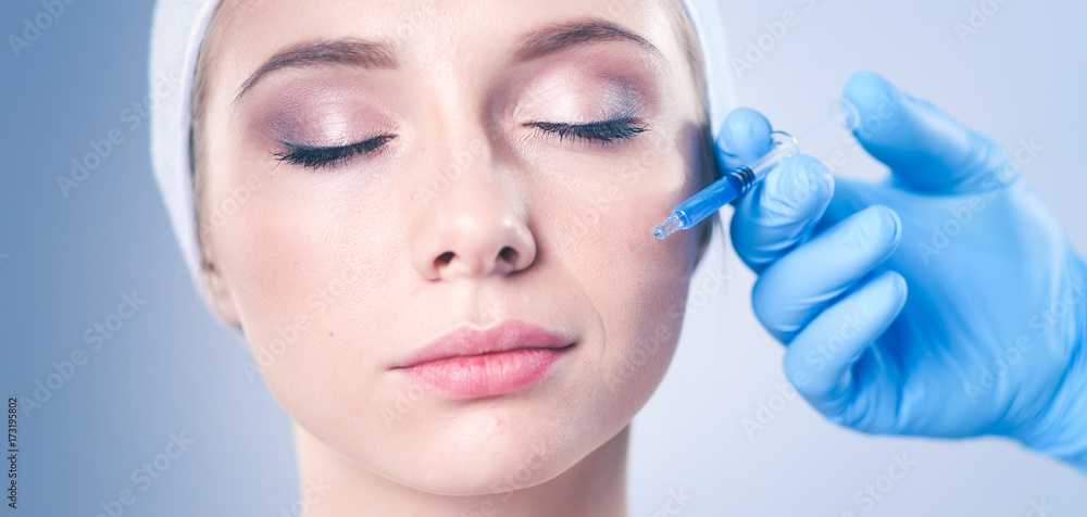 Cosmetic injection the pretty woman face. Isolated on gray background