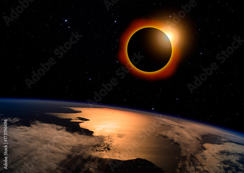 Solar eclipse with orange halo over the planet Earth, on dark starry sky