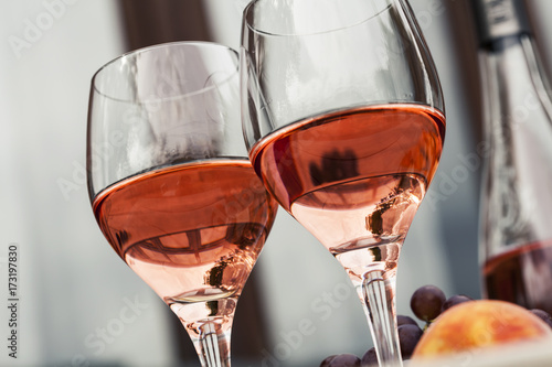 Fototapeta Naklejka Na Ścianę i Meble -  Two glasses of rose wine and board with fruits, bread and cheese on wooden table