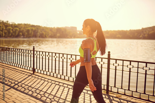 A sporty girl is walking in a sporting walk in the park by the lake. photo