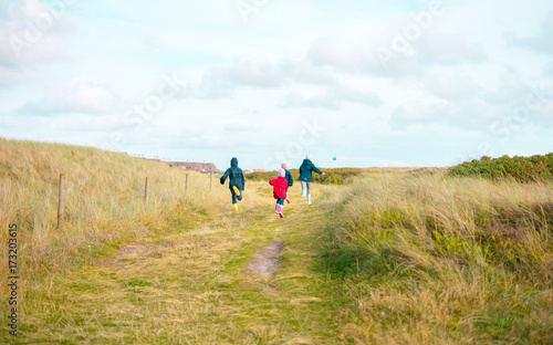 Kids children running between dunes in danish Denmark North Sea near blåvand