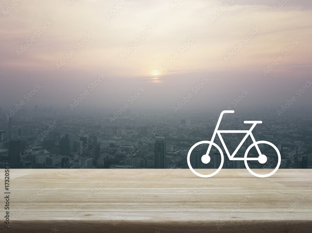Fototapeta premium Bicycle flat icon on wooden table over aerial view of cityscape at sunset, vintage style, Healthy lifestyle concept
