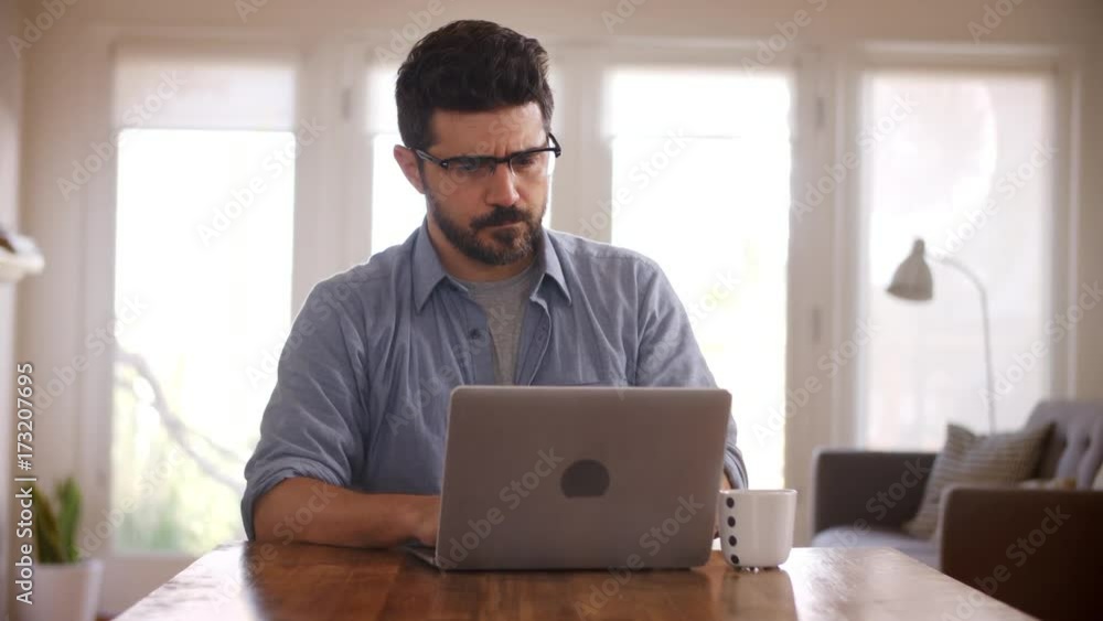 Man Working From Home Using Laptop On Dining Table Man Working From Home Using Laptop On Dining Table
