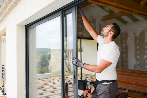 handsome young man installing bay window in a new house construction site photo