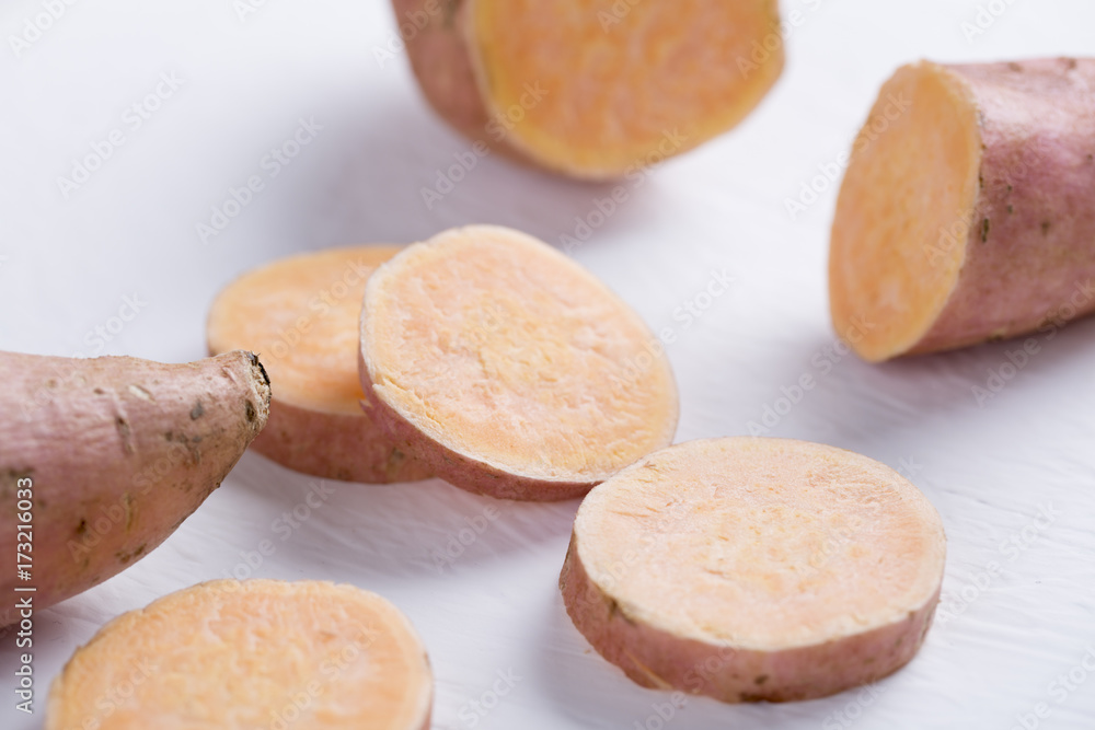 Closeup of raw sweet potato on white table. Slices. Closeup of raw sweet potato on white table. Slices.