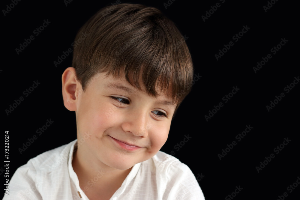 little child looking down smiling in a black background little child looking down smiling in a black background
