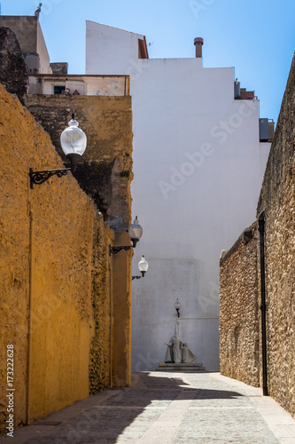 A small alleyway in the coastal city of vinaros spain with an old statue at the end