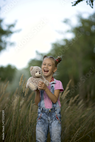Girl with teddy bear playing in the park