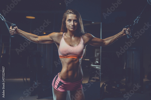Sexy athletic young girl training arms in gym