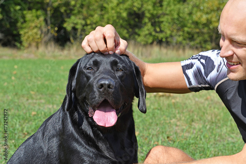 Fotografie Black dog with boy in the park at sunny day.