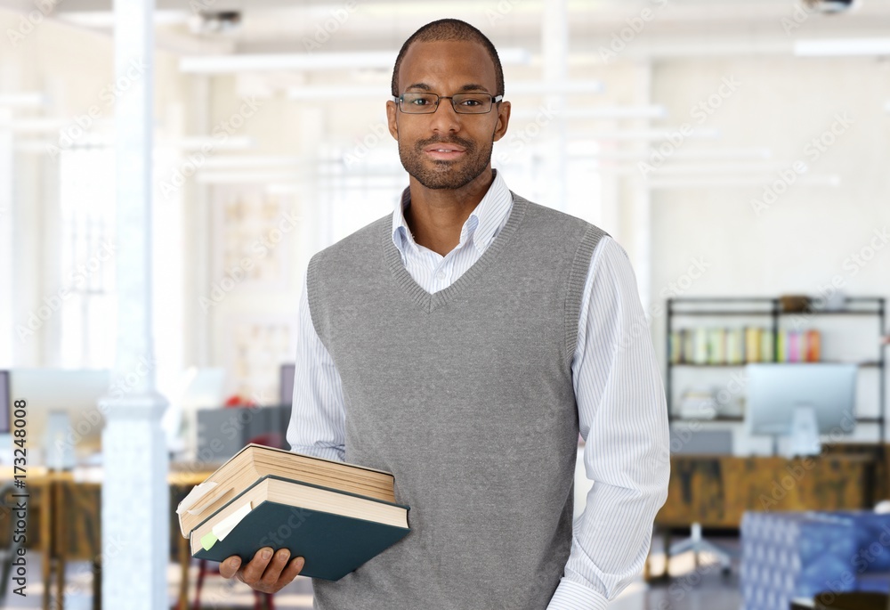 Young smart black man holding books in office Young smart black man holding books in office