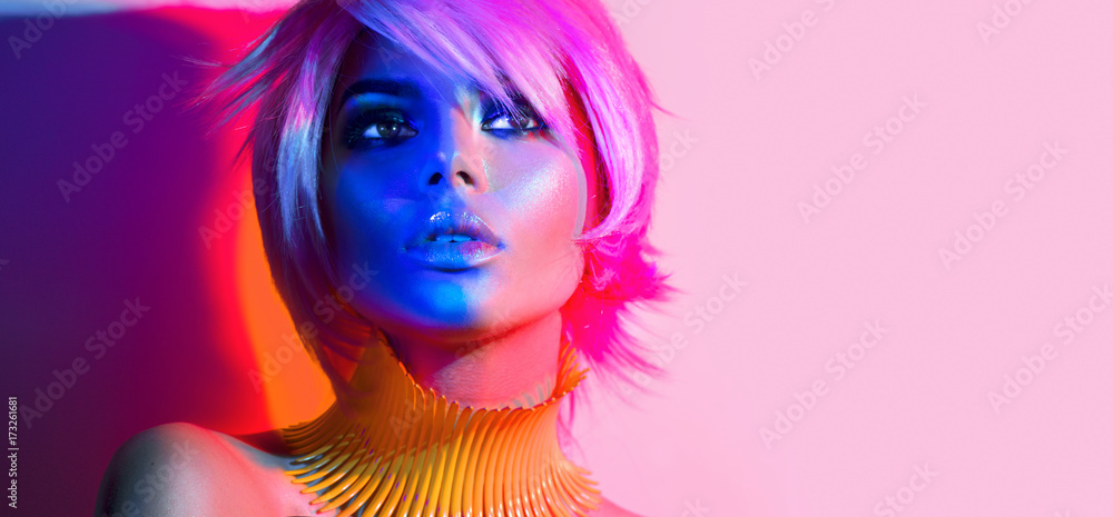 Fashion model woman in colorful bright lights posing. Portrait of beautiful sexy girl with trendy makeup and haircut