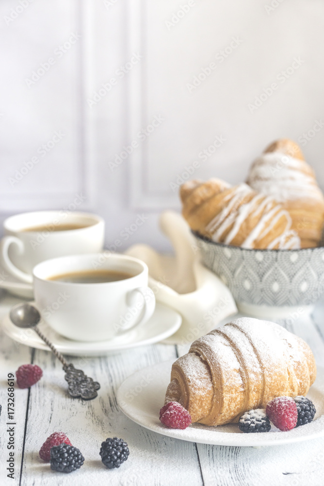 Croissants with fresh berries and two cups of coffee