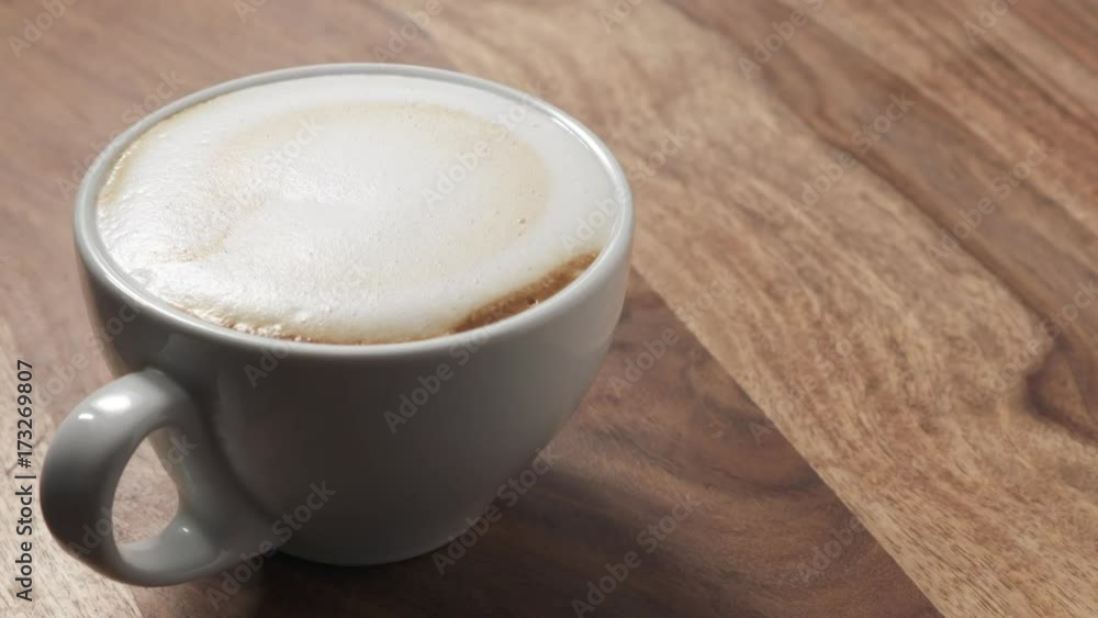 Slow motion cappuccino cup on wooden table with bubbles burst Slow motion cappuccino cup on wooden table with bubbles burst