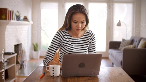 Woman Working From Home Using Laptop On Dining Table photo