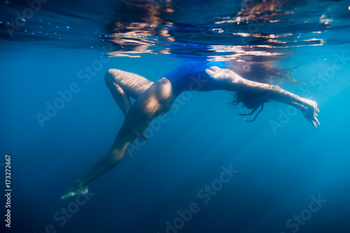 Woman floating in sea  underwater in blue ocean