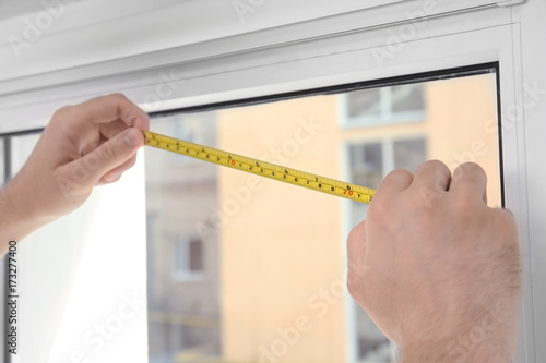 Young man installing window screens indoors