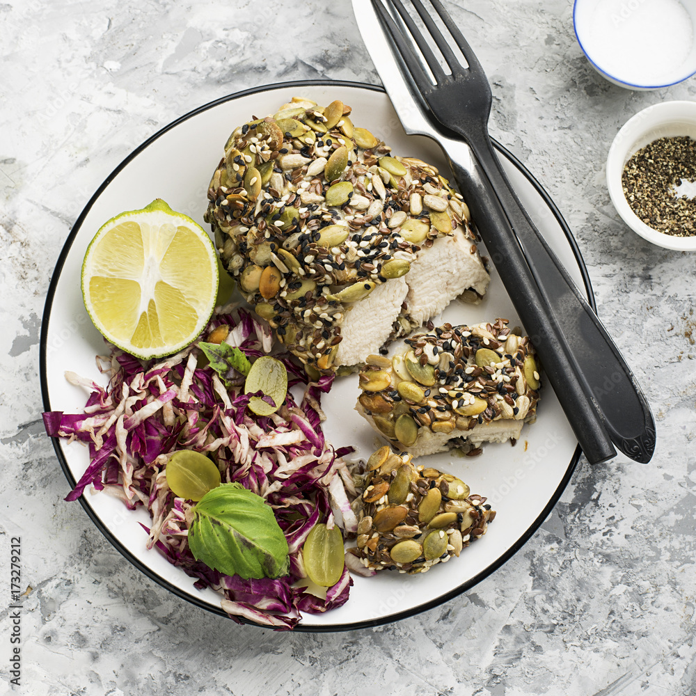 A healthy snack lunch. Baked chicken breast in breaded LSA pumpkin seeds, flax seeds, sunflower seeds, almonds for crispy appetizing crust with radicchio salad, green grapes with basil in a plate on