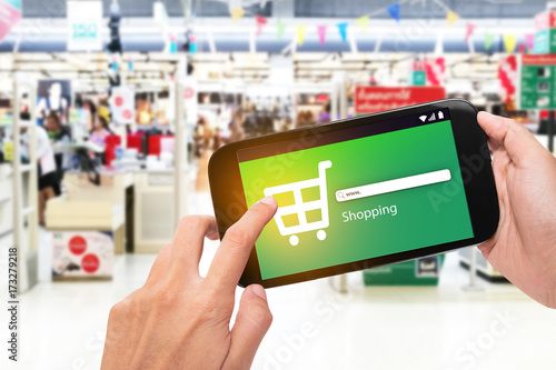 Hand holding mobile phone at supermarket checkout background, e coupon concept