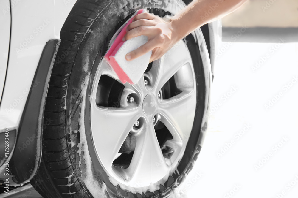 Man washing automobile wheel with sponge Man washing automobile wheel with sponge