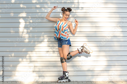 Young woman on roller skates near fence