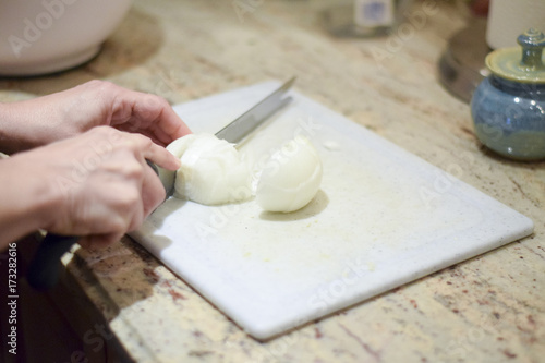 Hand chopping onion on cutting board