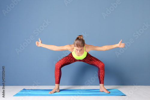Young woman practicing yoga pose near color wall indoors