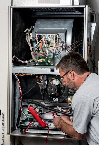 Photo Master technician works on a home furnace with volt meter