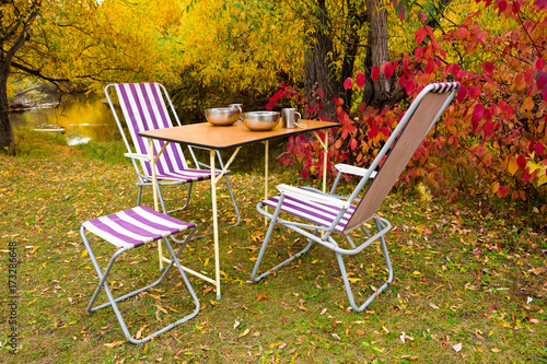Camping table and chairs in the autumn forest on the river bank  © Windofchange64